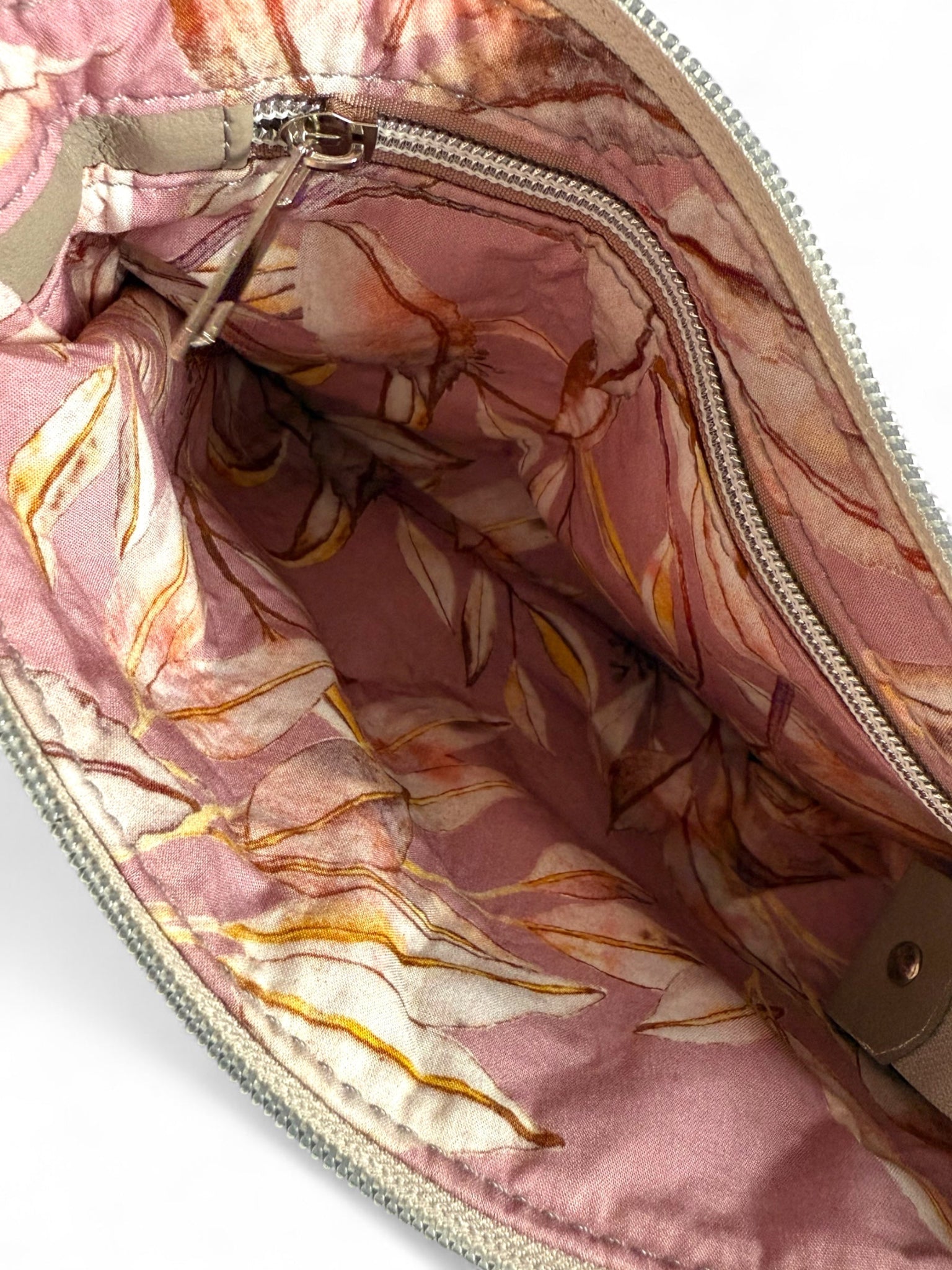 Interior of Starburn bag with dusty pink leaf lining. It shows the interior zip which contains and integrated purse, UK handmade leather bag by Lilly & Jude.