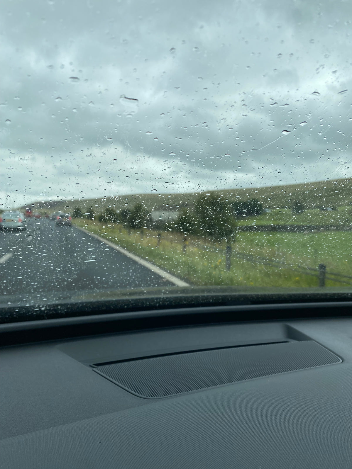 POV through a rain-covered windscreen from inside a car – moody, reflective small biz vibes.