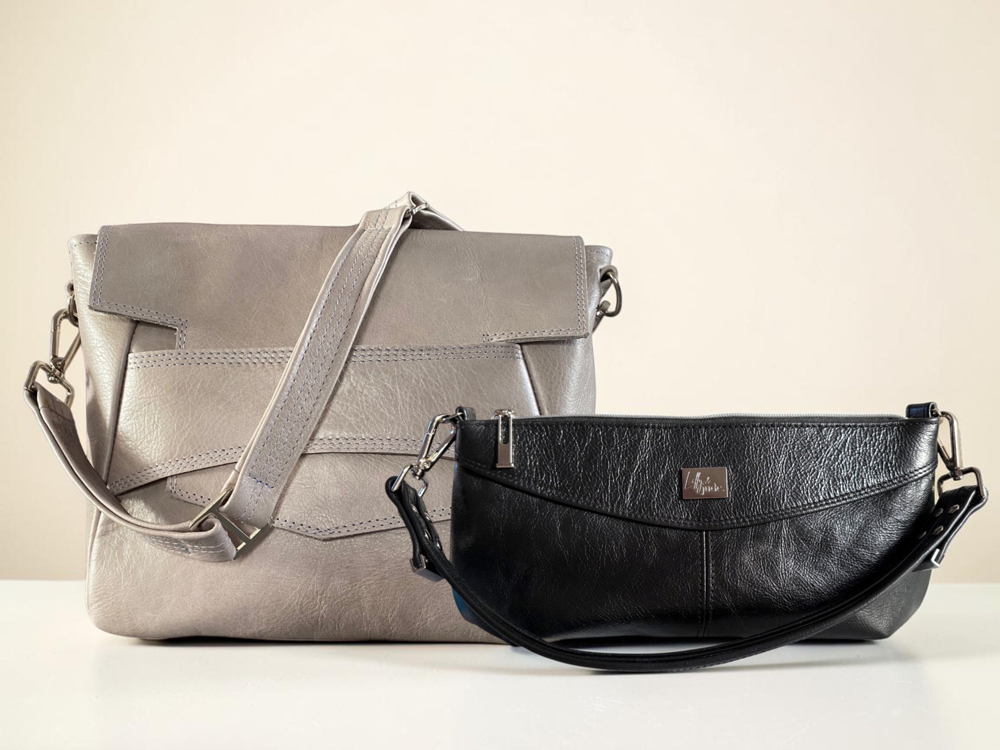 A grey leather messenger style women's bag and a black leather handbag on a neutral background