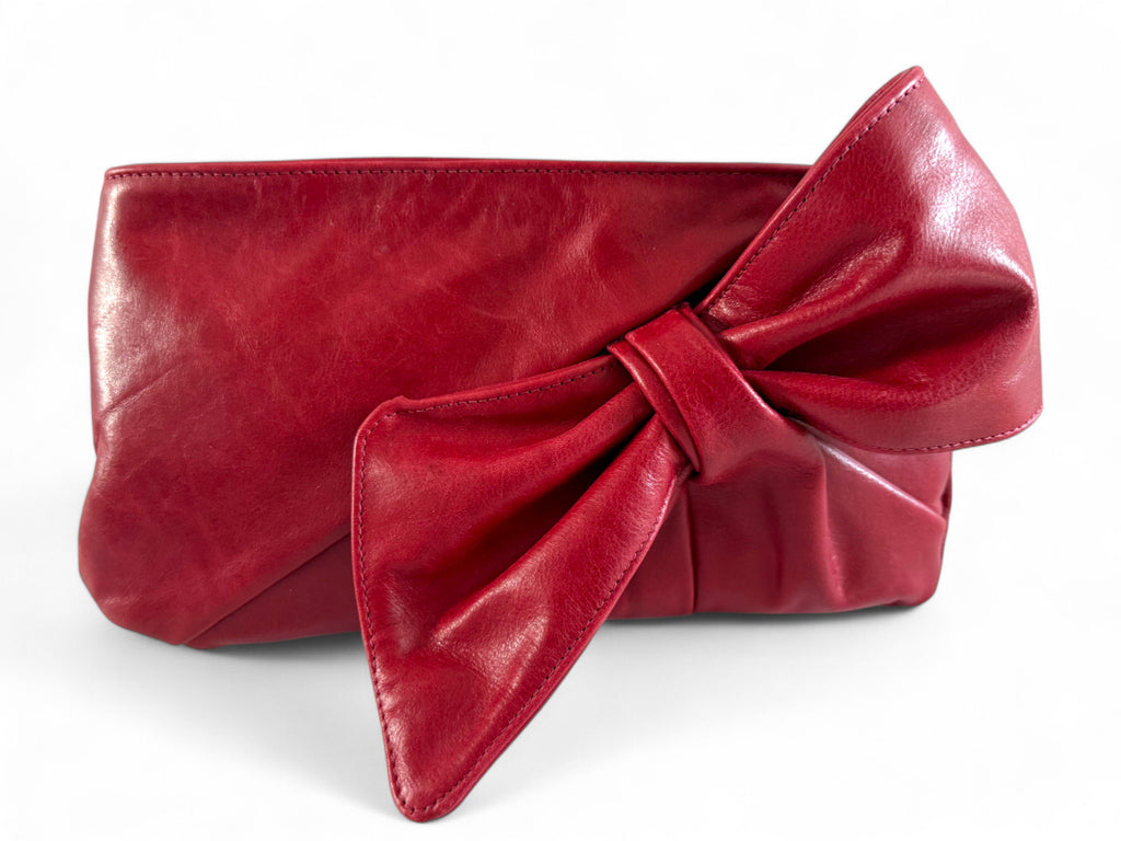 Deep red leather clutch bag with a large bow on a white background. Handcrafted by Lilly & Jude using rescued leather