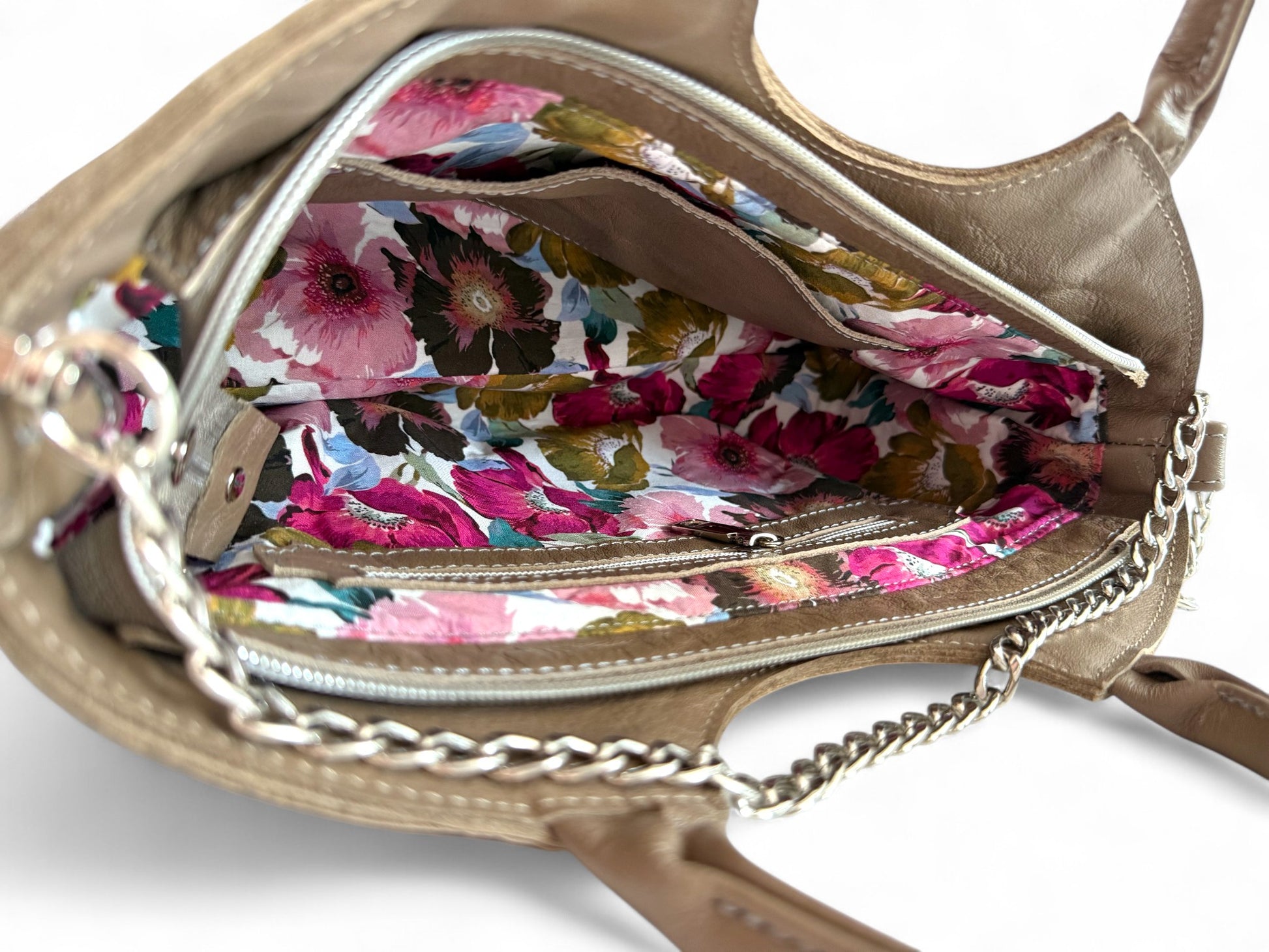 A peek inside the Flossy handbag, showing the floral lining. The bag is made from taupe coloured rescued leather and the lining is in shades of pinks, purples, greens and blues.