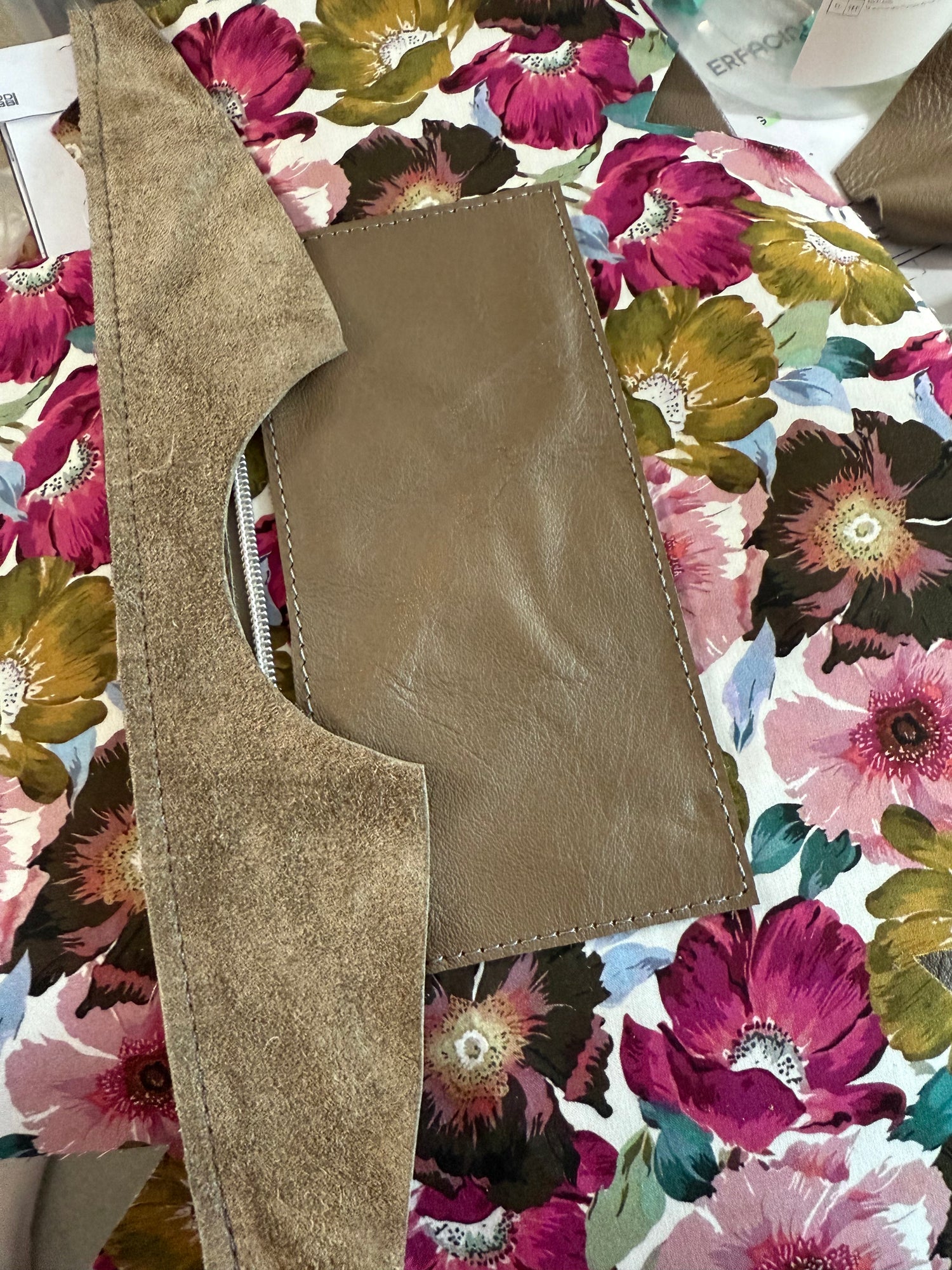 Beige leather bag pattern pieces on a floral fabric background
