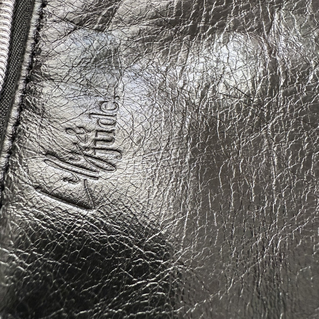 Close-up of a textured black leather surface with a brand logo.