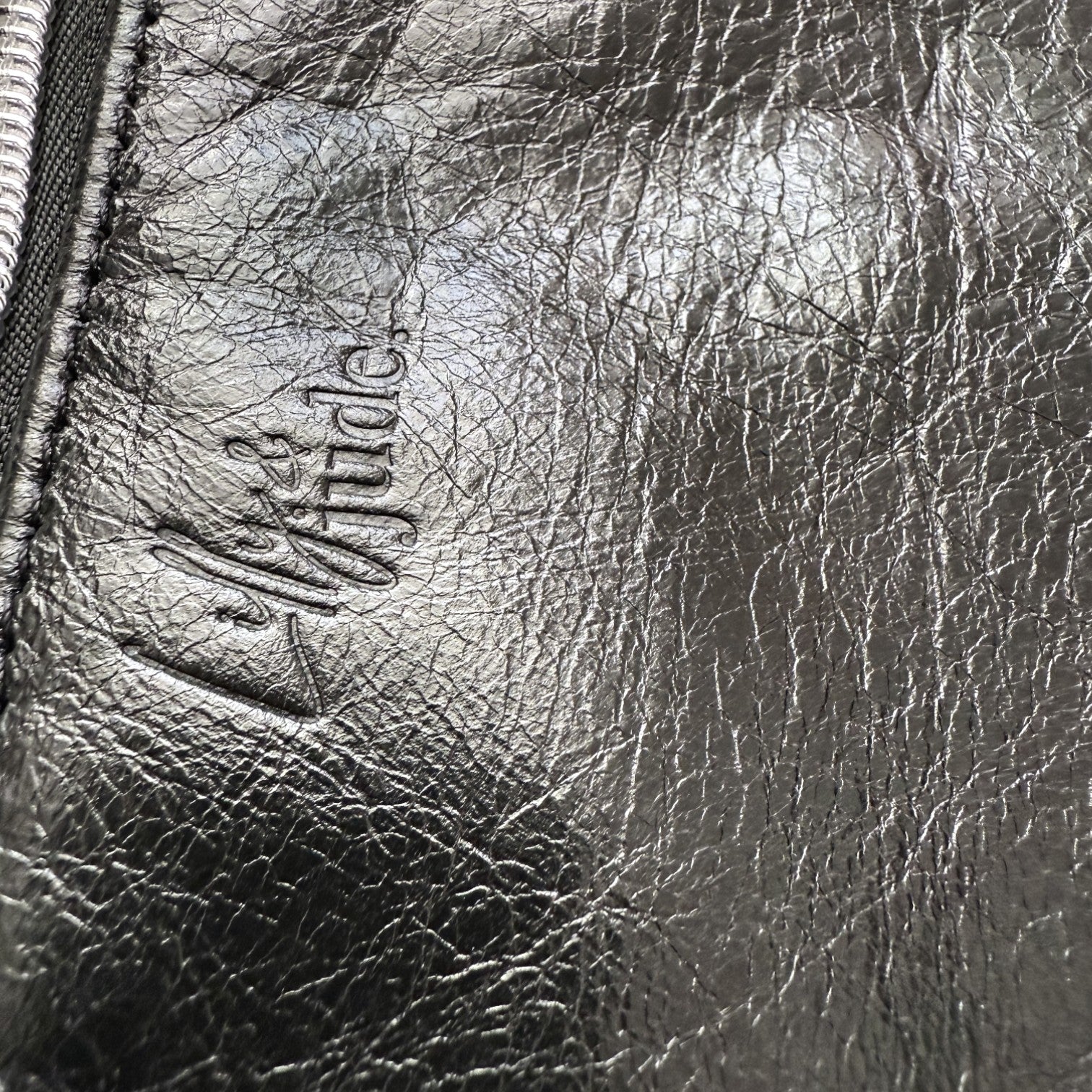 Close-up of a textured black leather surface with a brand logo.