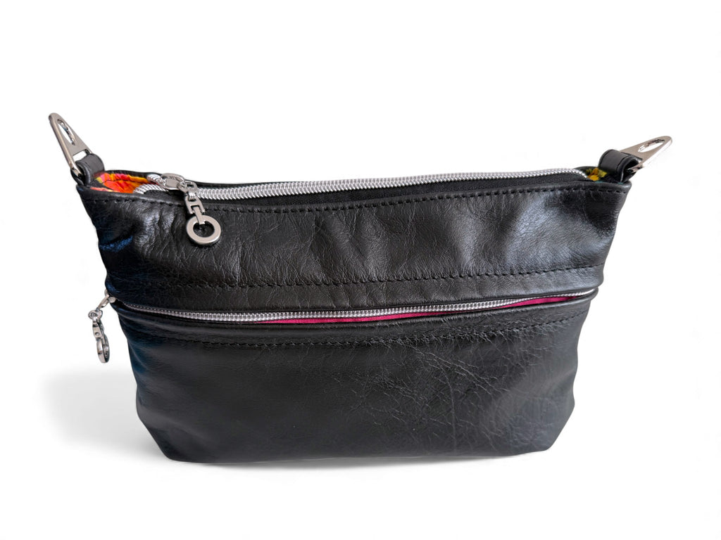 Black leatherhandbag with silver zippers and hardware on a white background