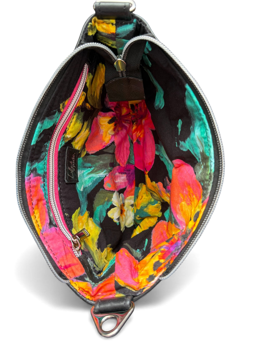Open, black leather handbag with a colorful floral-patterned lining on a white background