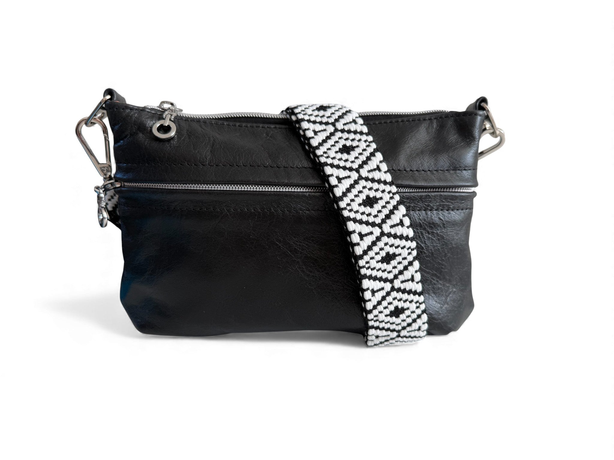 Black leather crossbody bag with a white and black patterned strap on a white background