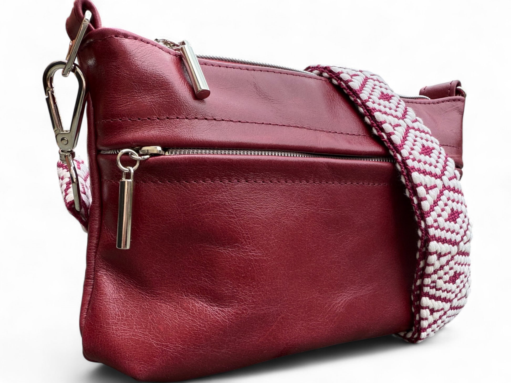 Deep red leather handbag with a patterned strap, showing the detail of the silver hardware  on a white background