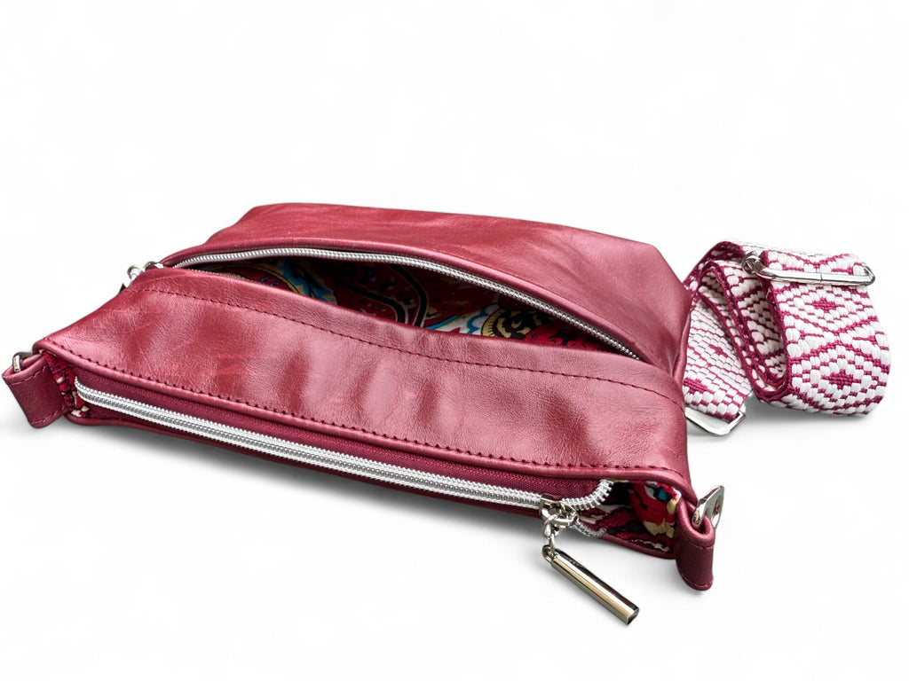 Burgundy bag laid flat showing soft rescued leather texture. The front pocket is open and you can see a glimpse of the lining
