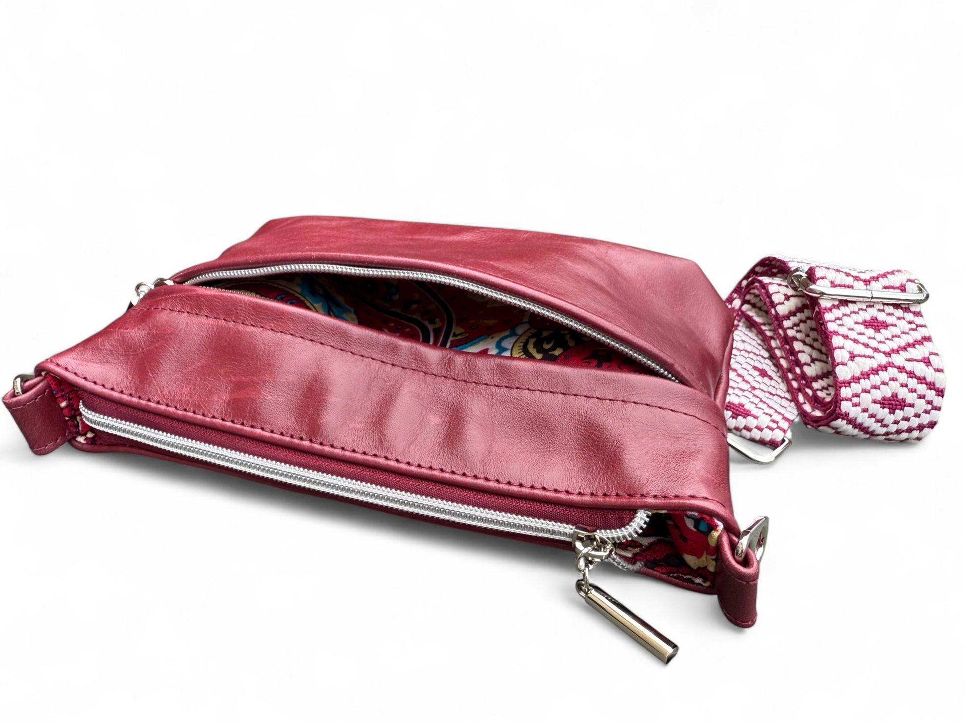 Burgundy bag laid flat showing soft rescued leather texture. The front pocket is open and you can see a glimpse of the lining
