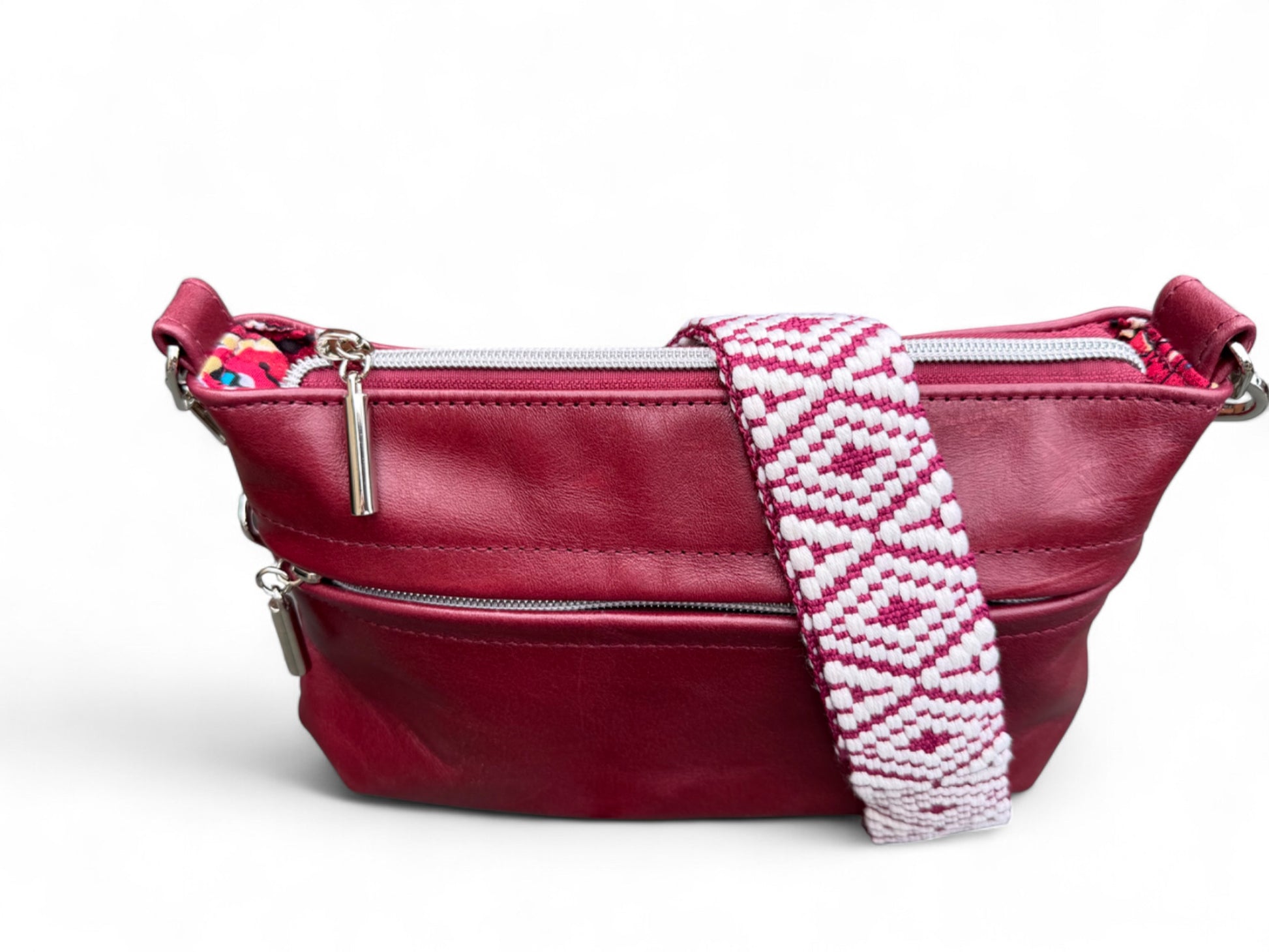 Dark red crossbody handbag with a patterned strap on a white background