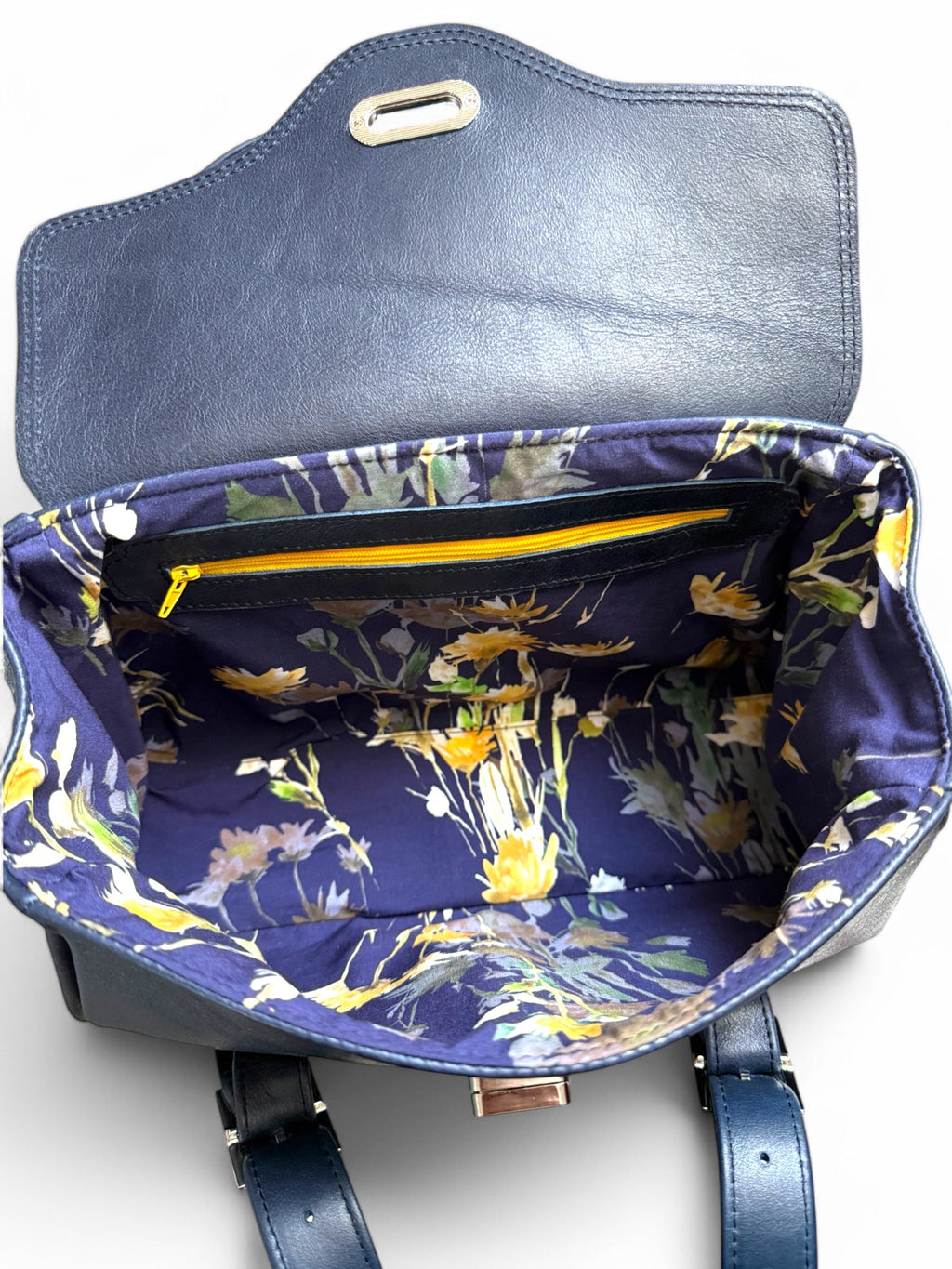 Blue leather handbag with navy and yellow floral interior lining and yellow zippered  pocket