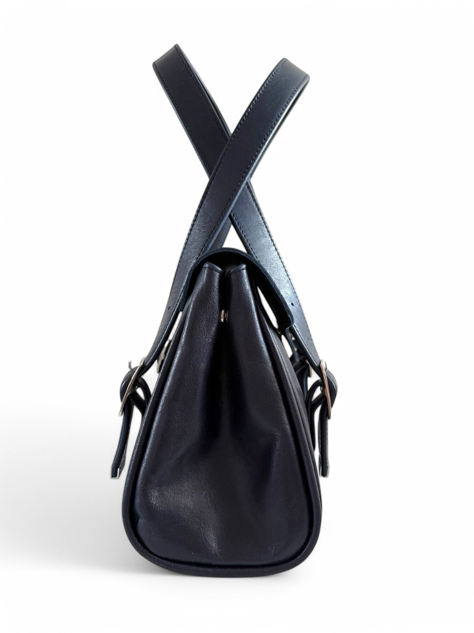Side view of a navy blues leather handbag with a white background