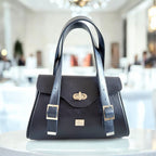 Black handbag with blue straps on a table in a blurred interior background