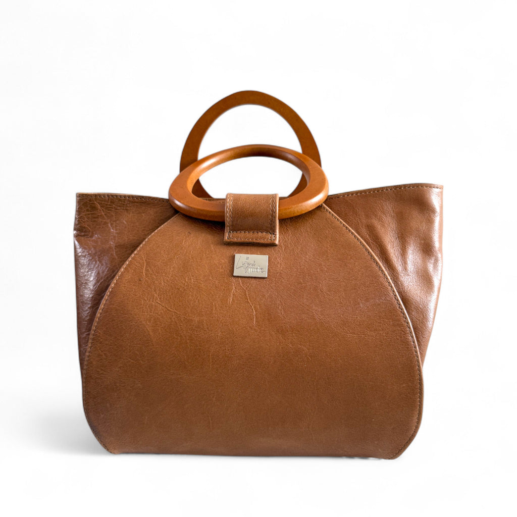 Tan leather handbag with wooden handles on a white background, handcrafted by Lilly & Jude in the UK.
