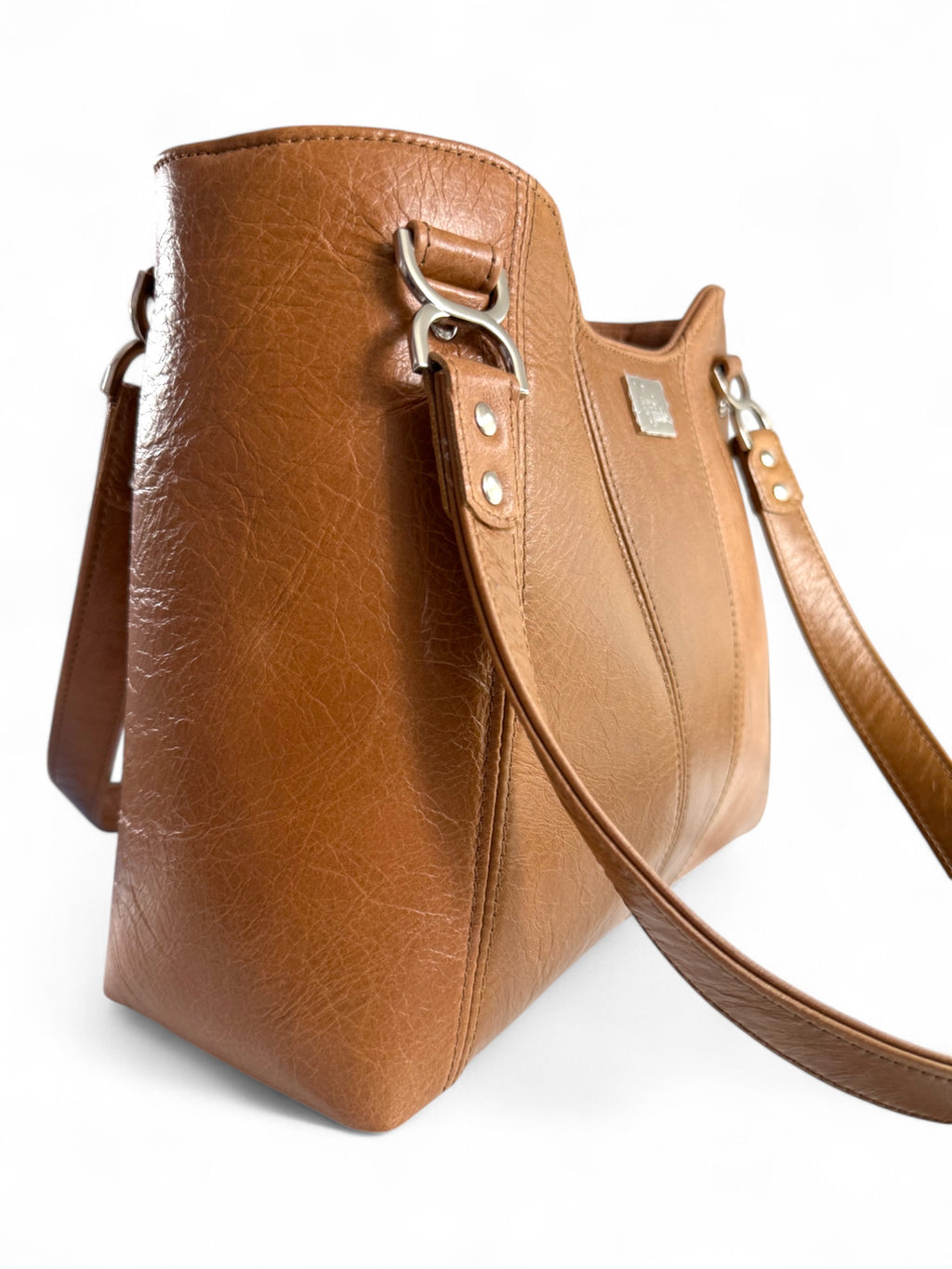 Tan brown leather, panelled handbag with a strap and silver hardware on a white background
