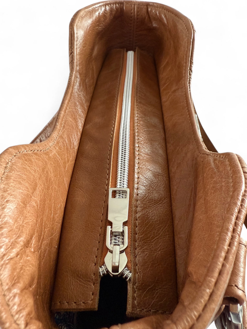 Close-up view of the silver zipper opening on the tan brown leather Alaula handbag. Handcrafted from rescued leather