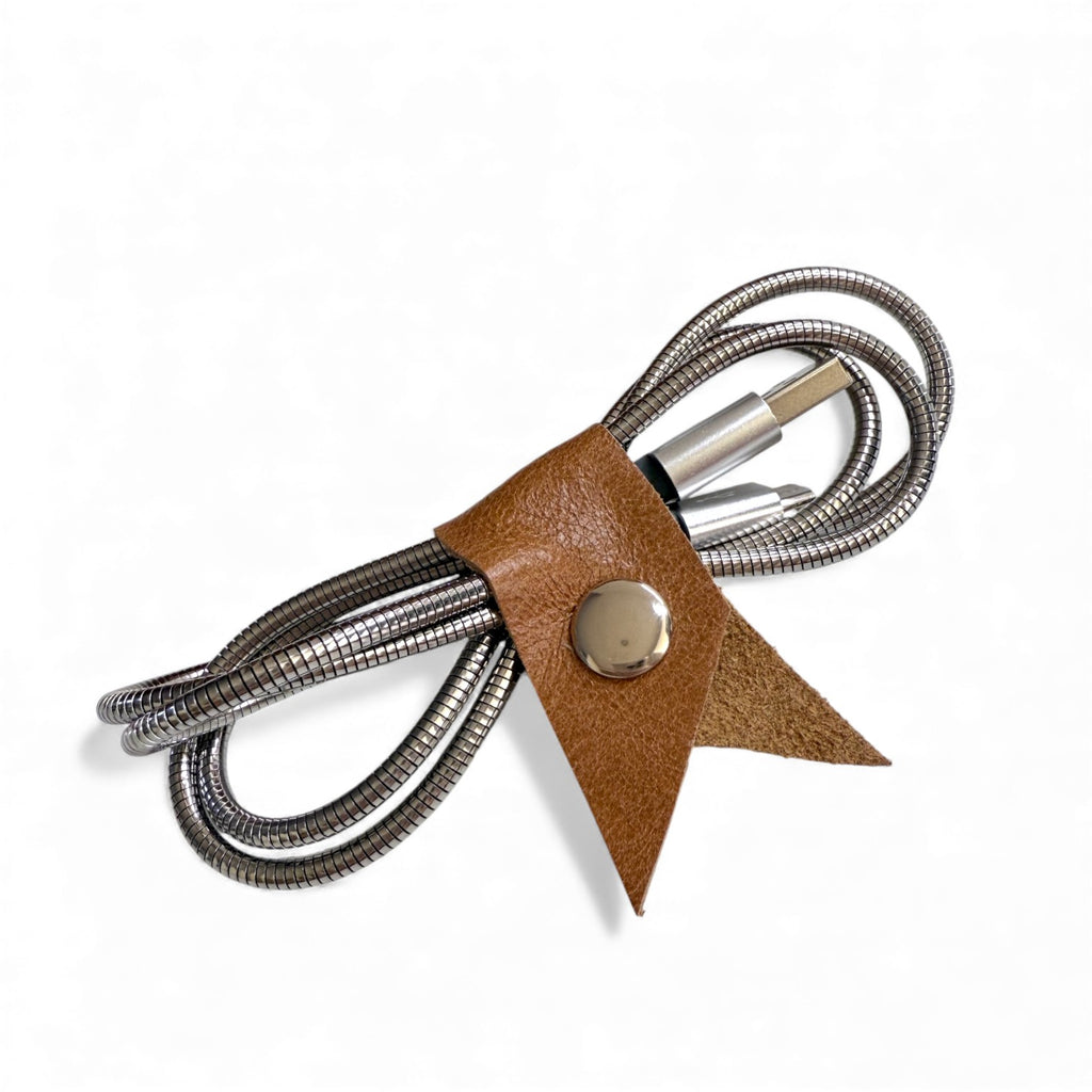 Tan leather Cable Keeper. Coiled cable with a brown leather strap and metal button on a white background 
