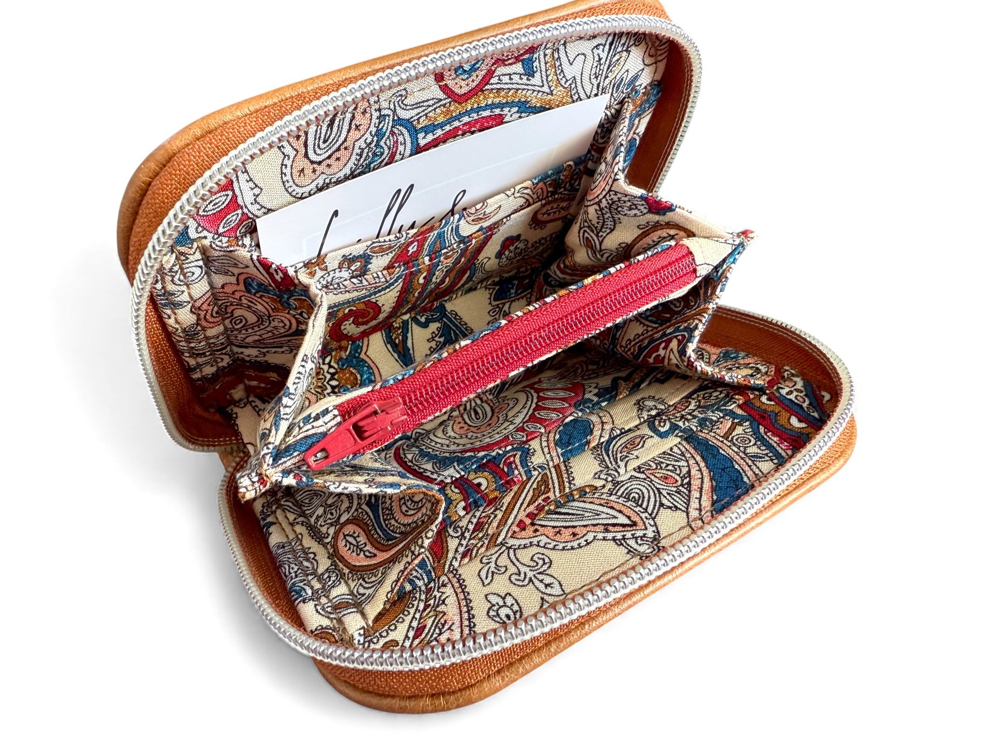 Tan leather purse with cream paisley patterned lining, showing the card slots and burgundy zippered coins pocket