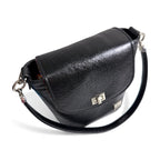 Top, front view of the Belle bucket bag, showing the silver twist lock on the front flap and hardware of the strap and connectors