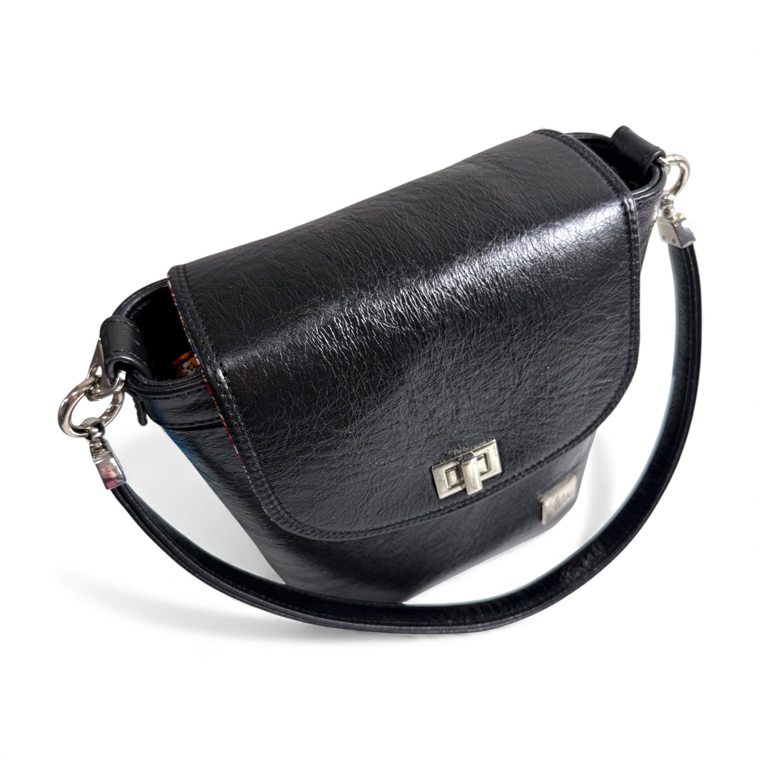 Top, front view of the Belle bucket bag, showing the silver twist lock on the front flap and hardware of the strap and connectors