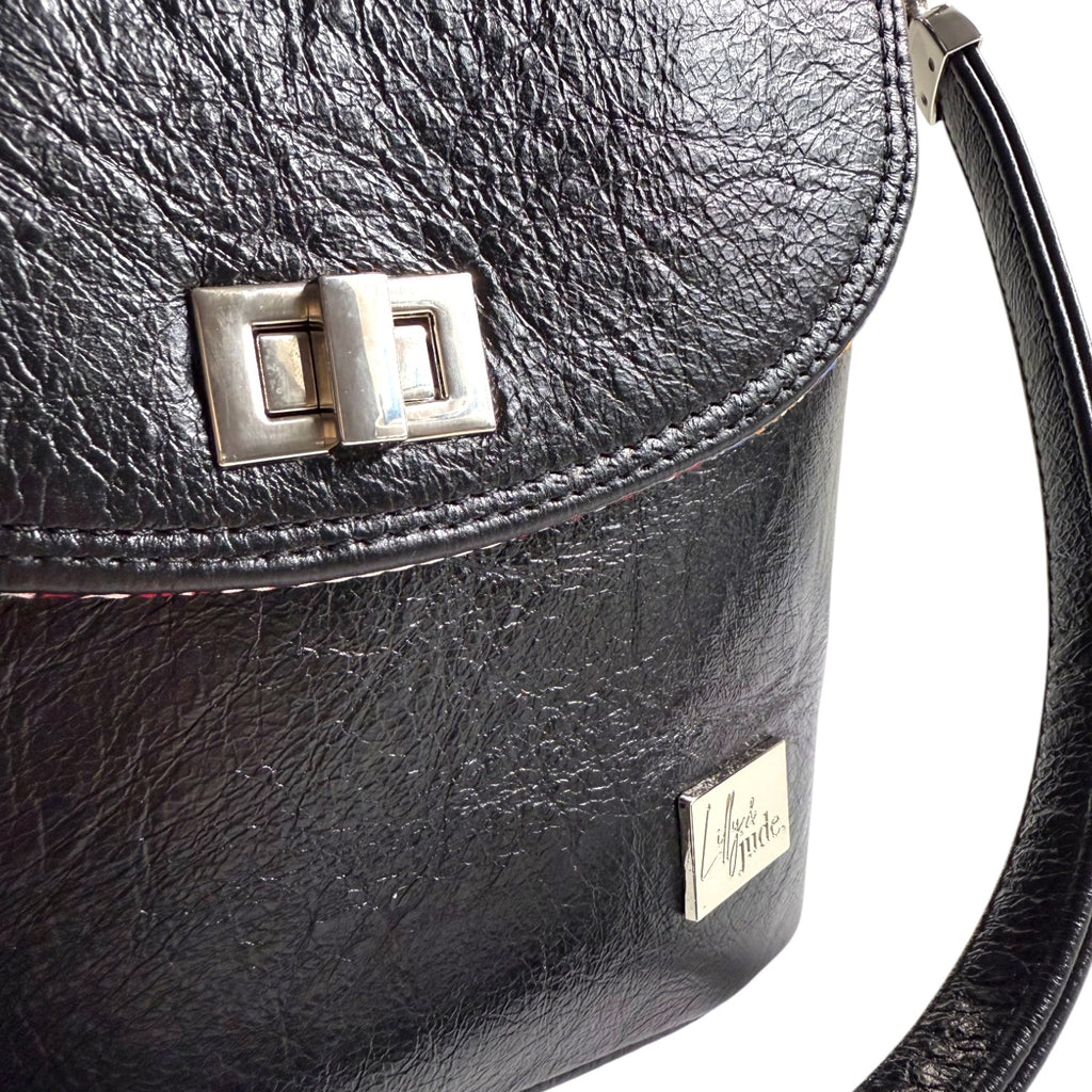 Close up view of the Belle bucket handbag, highlighting the silver twist lock and silver logo'd badge on the front. Sustainable fashion accessories by Lilly & Jude