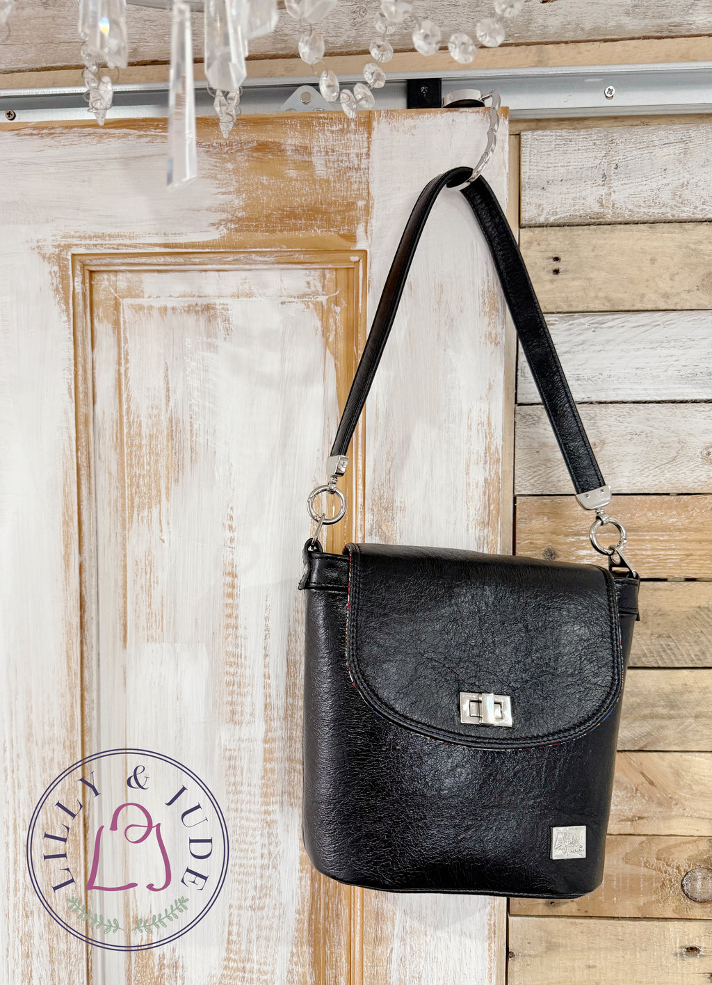 Lilly & Jude Belle bucket handbag, hanging from the top corner of a rustic looking door
