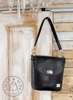 Lilly & Jude Belle bucket handbag, hanging from the top corner of a rustic looking door
