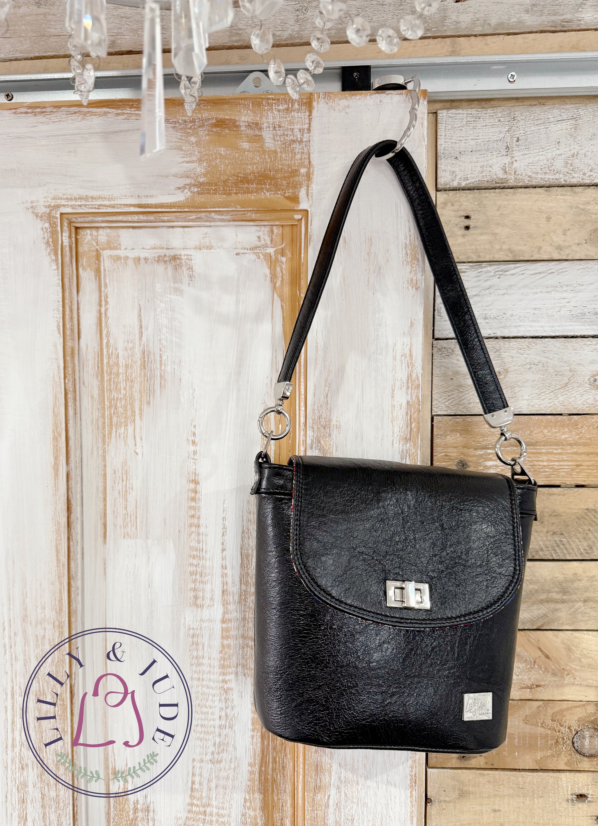 Lilly & Jude Belle bucket handbag, hanging from the top corner of a rustic looking door