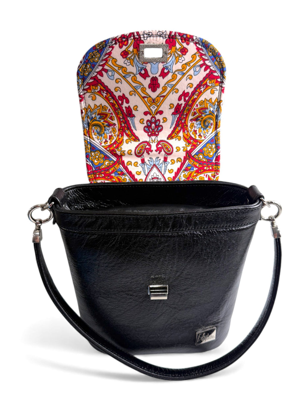 Front view of the Belle bucket bag, with the flap open to show an incredible, red yellow and blue patterned  lining. Beautiful, handcrafted handbag, using black rescued leather