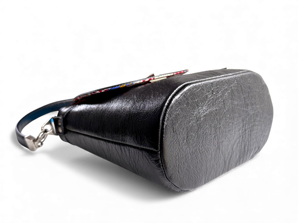 View of the base and side of the Belle Bucket handbag, against a white background. The bag is handcrafted from black rescued leather