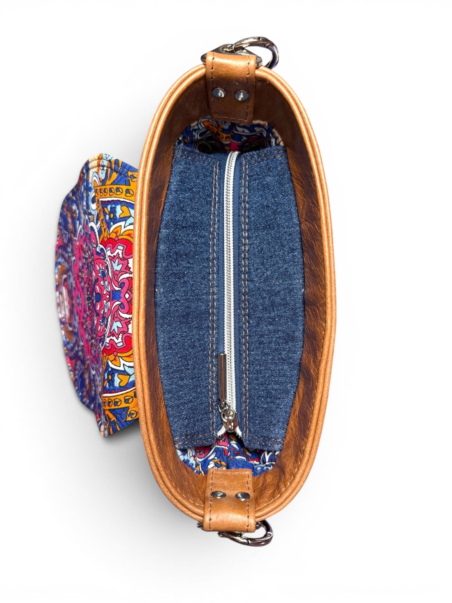 Birds eye view of the Belle bucketbag. The image shows the denim zipper placket, silver zip and the tan leather trim at the top of the bag. The bag is sat on a white background