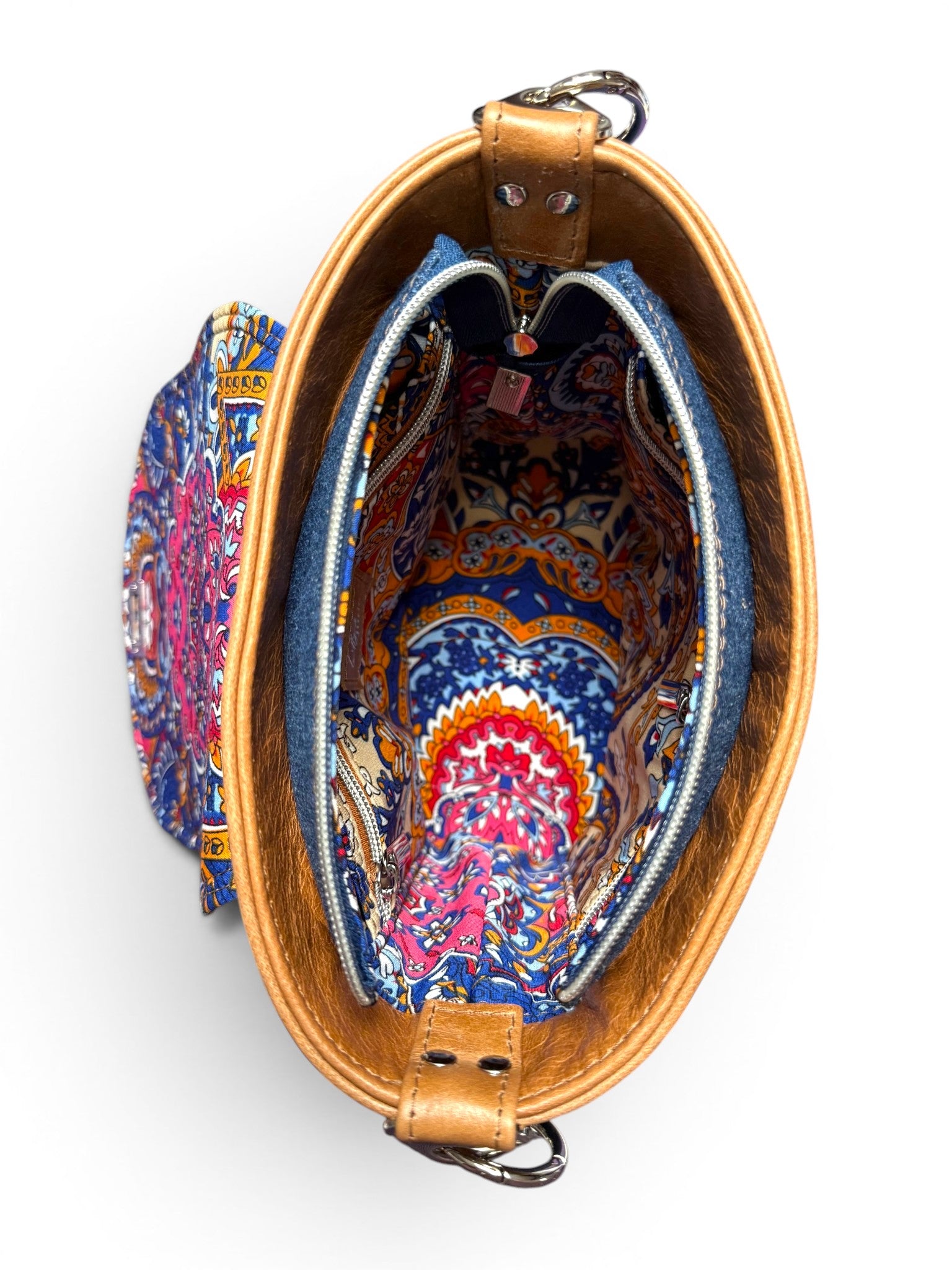 Birds eye view of the Belle bucketbag. The image shows the open zipper, colourful lining and the tan leather trim at the top of the bag. The bag is sat on a white background