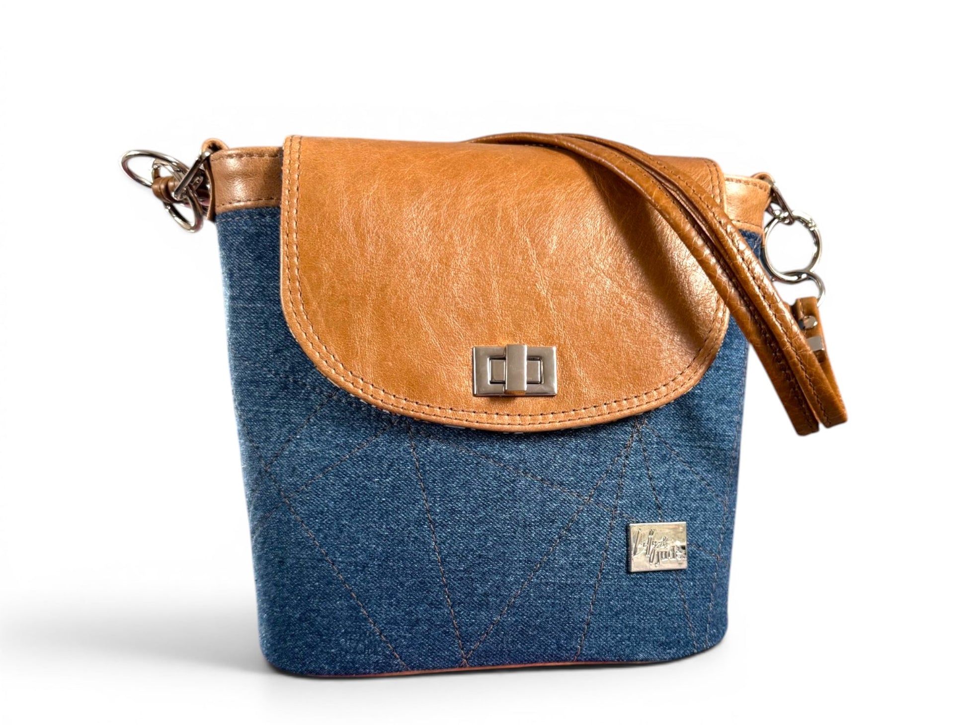 Blue denim and tan brown leather  bucket bag, with two strand strap, on a white background