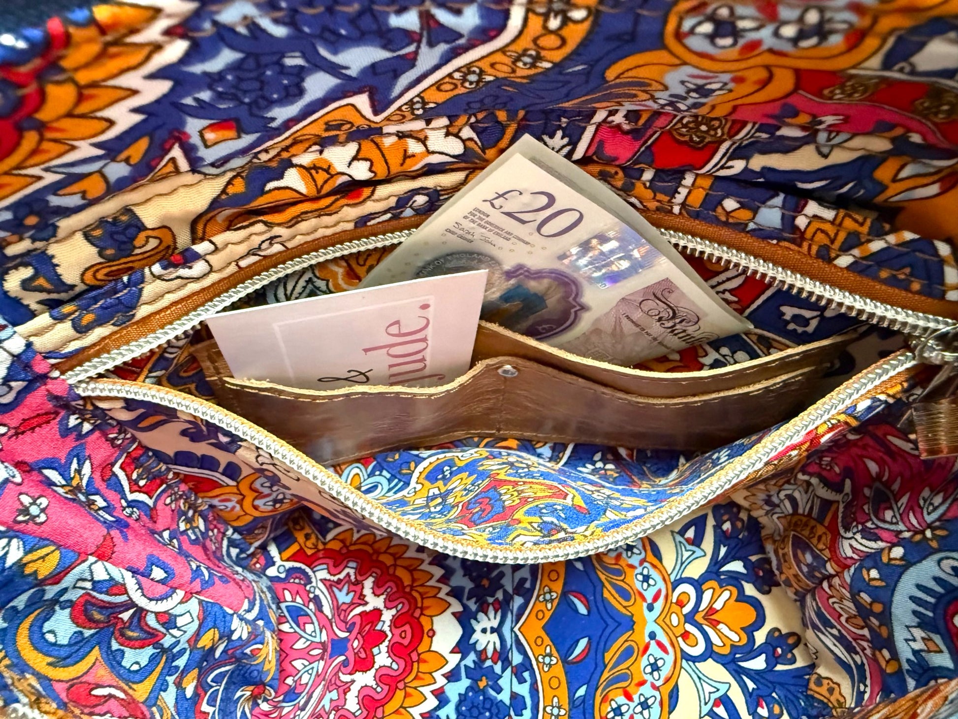 Interior view of the Belle Bucket Bag, showing the colourful lining and the integrated purse, with a card and cash