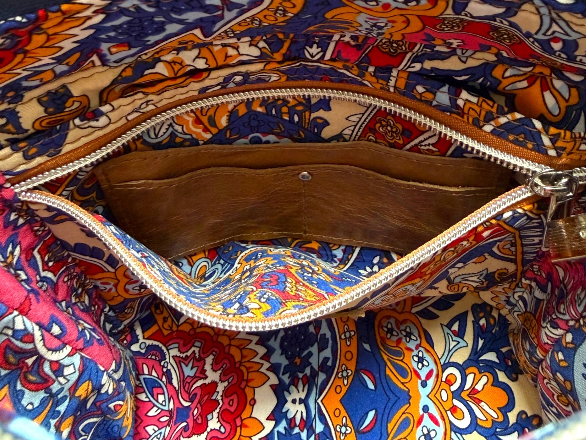 Interior view of the Belle bucket bag, showing the colourful fabric lining and open zipper pocket, to reveal the hidden integrated leather purse