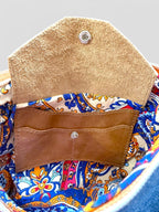 Close-up of a colorful fabric interior with a tan leather integrated pocket with the studded flap open