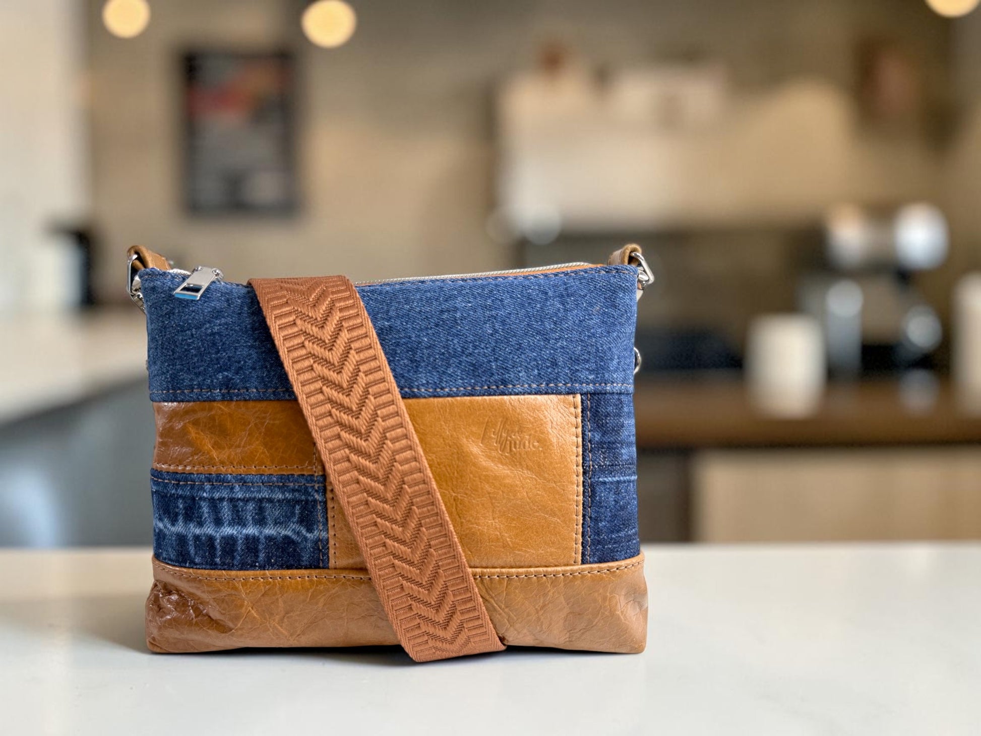 Denim and leather crossbody bag on a kitchen counter
