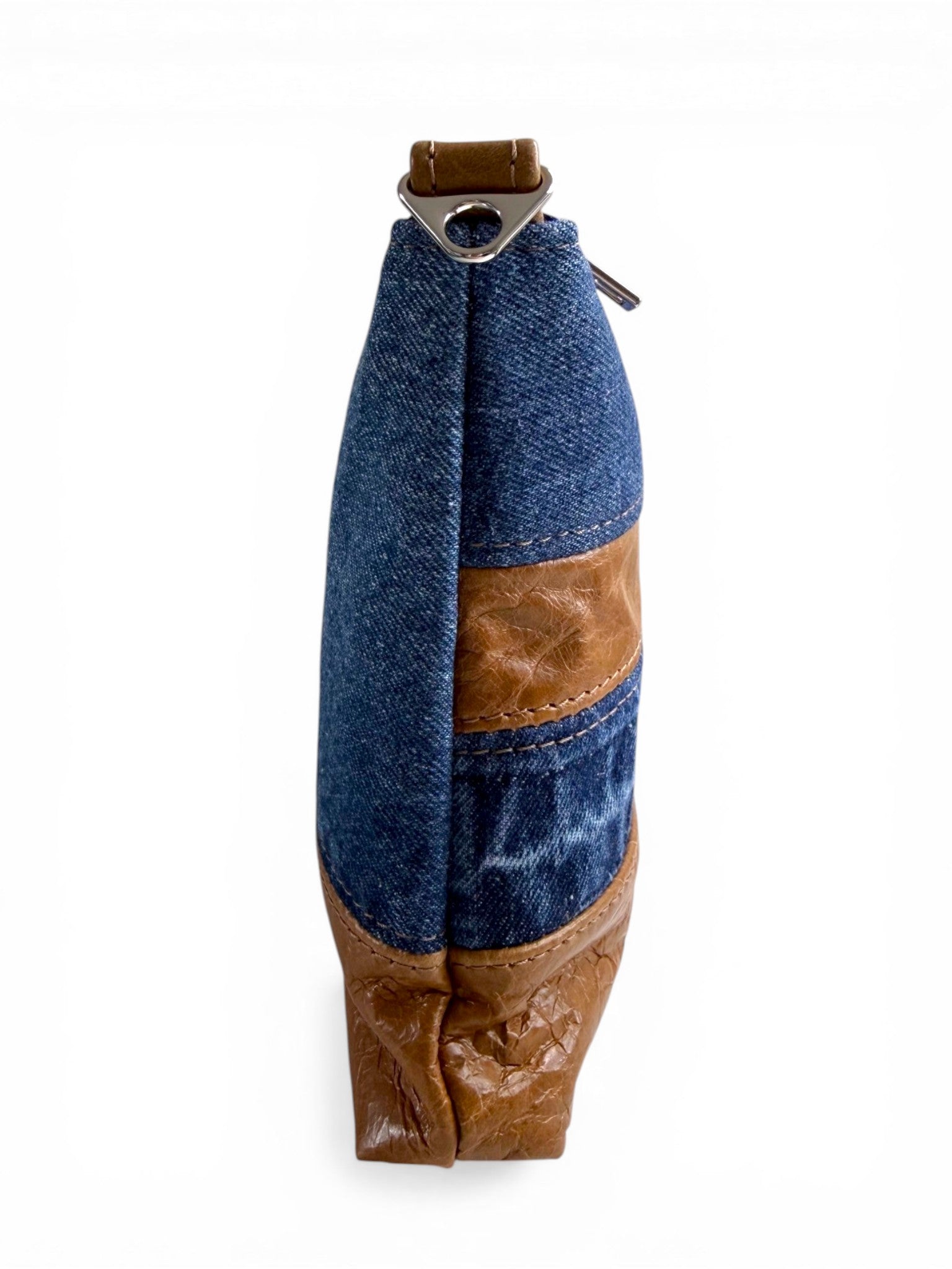 Side view of the denim and tan leather crossbody bag on a white background