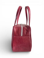 Side view of the dark red leather bowling bag, highlighting the silver zipper, against a white background