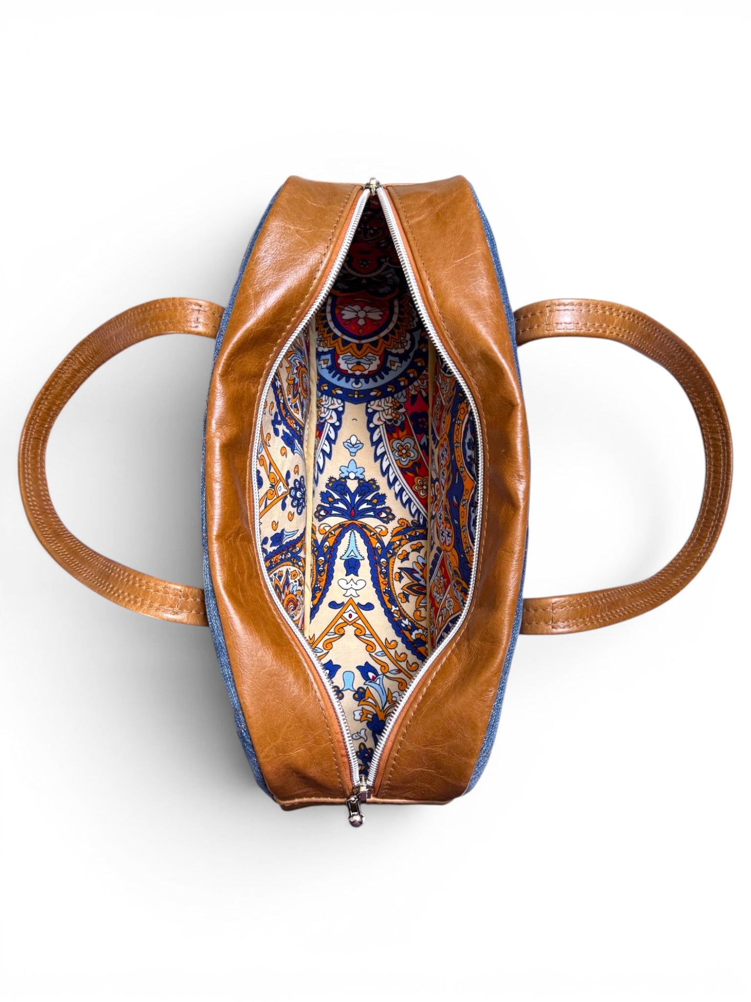 Birds eye view of the top of the Cassie bag, showing the patterned lining, on a white background