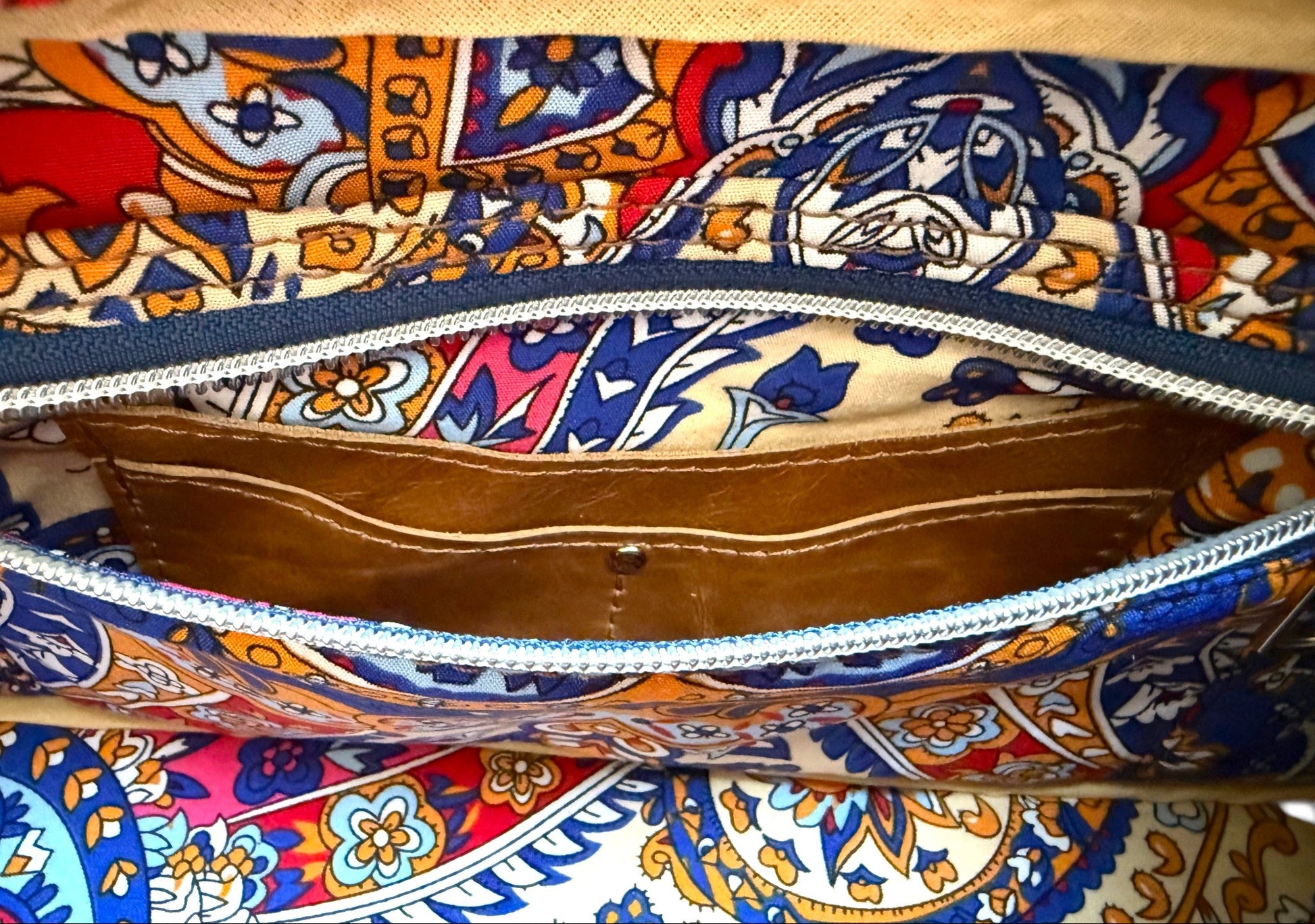 Interior view of the Cassie handbag, showing the lining fabric, slip/zip pocket and hidden, tan leather integrated purse