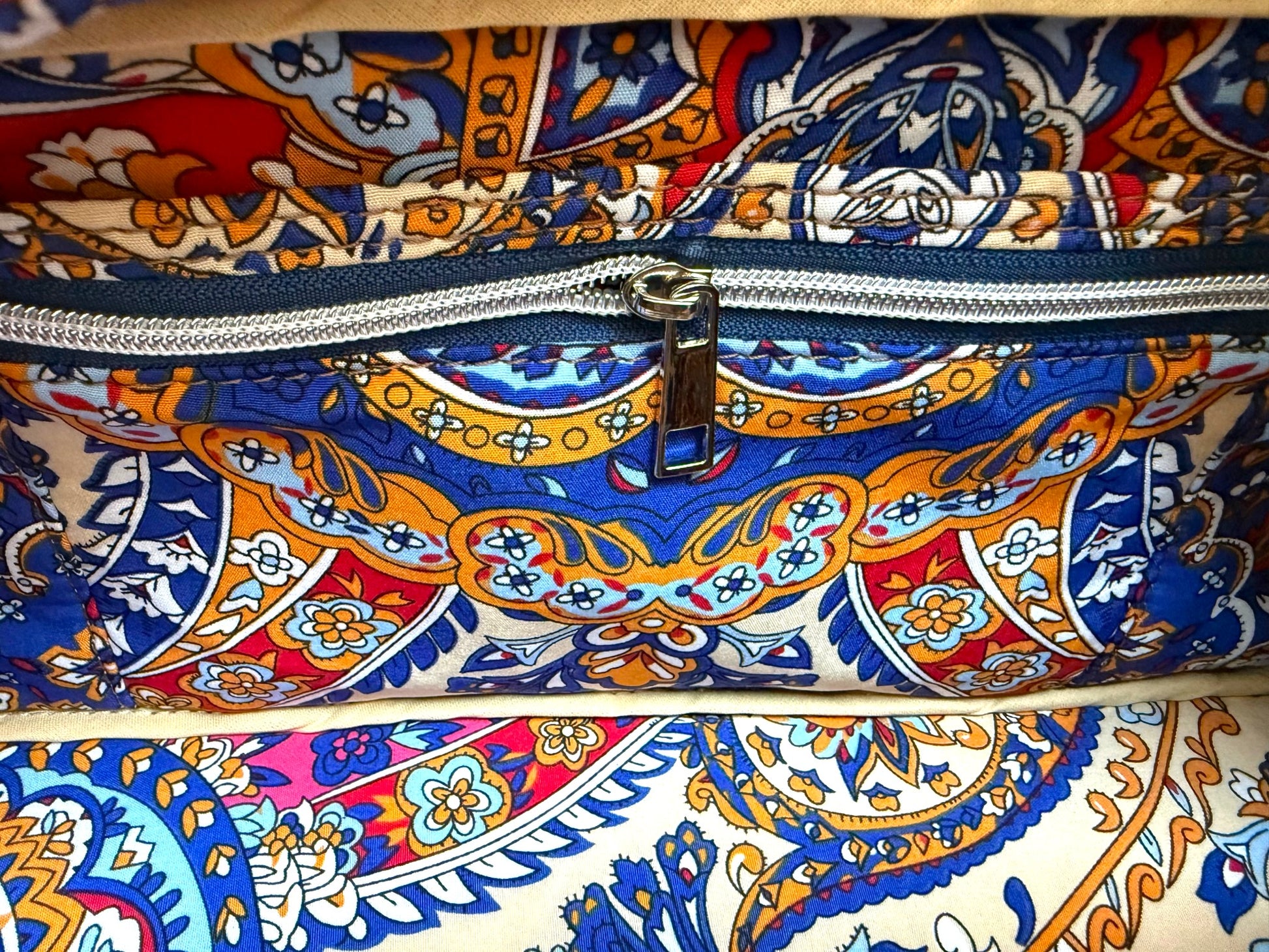Interior view of the denim and leather Cassie handbag, showing the closed zip/slip pocket and colourful, patterned lining fabric