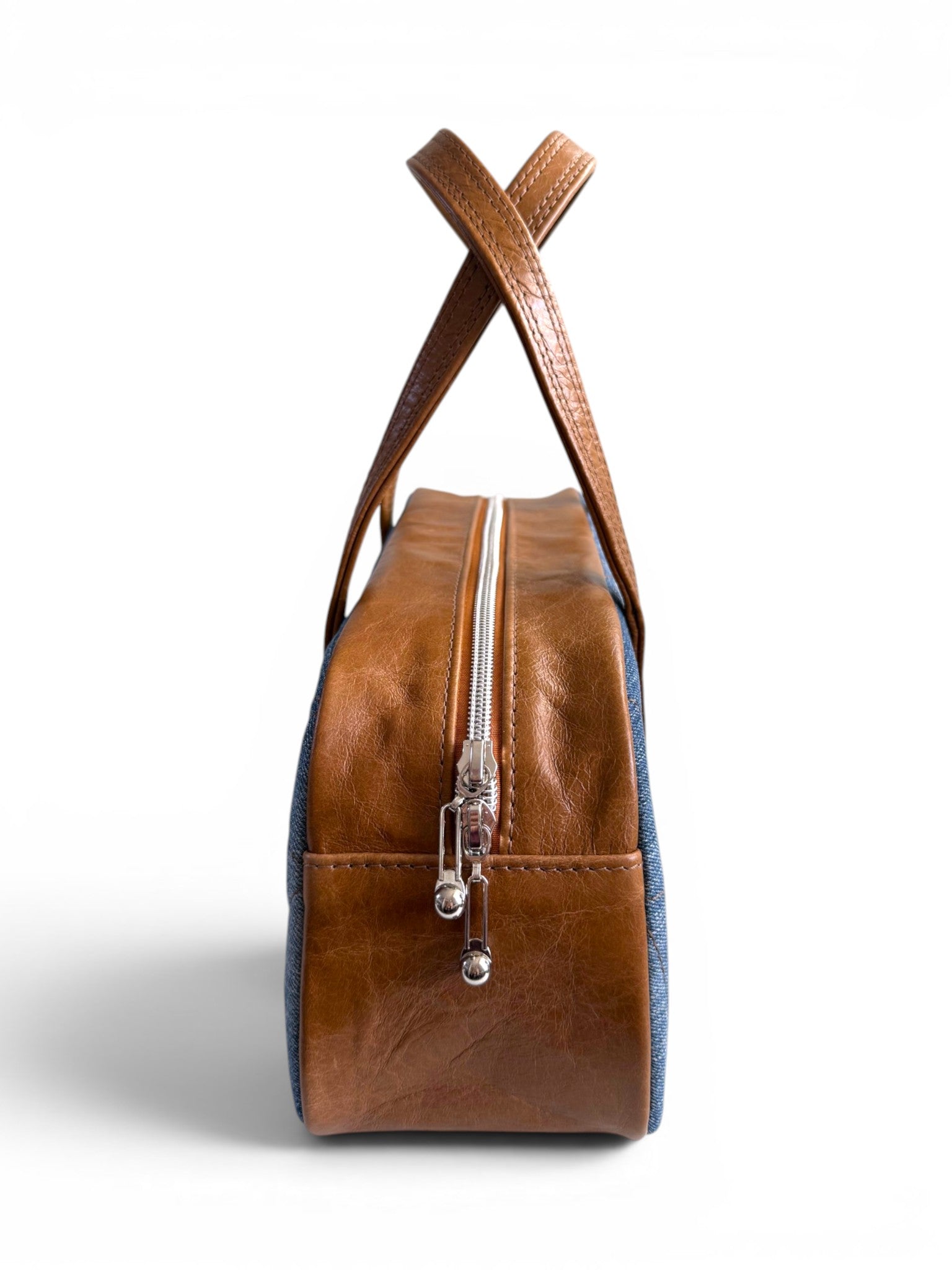 Side view of the Cassie handbag, showing the tan brown leather gusset, with a silver zipper on a white backgro