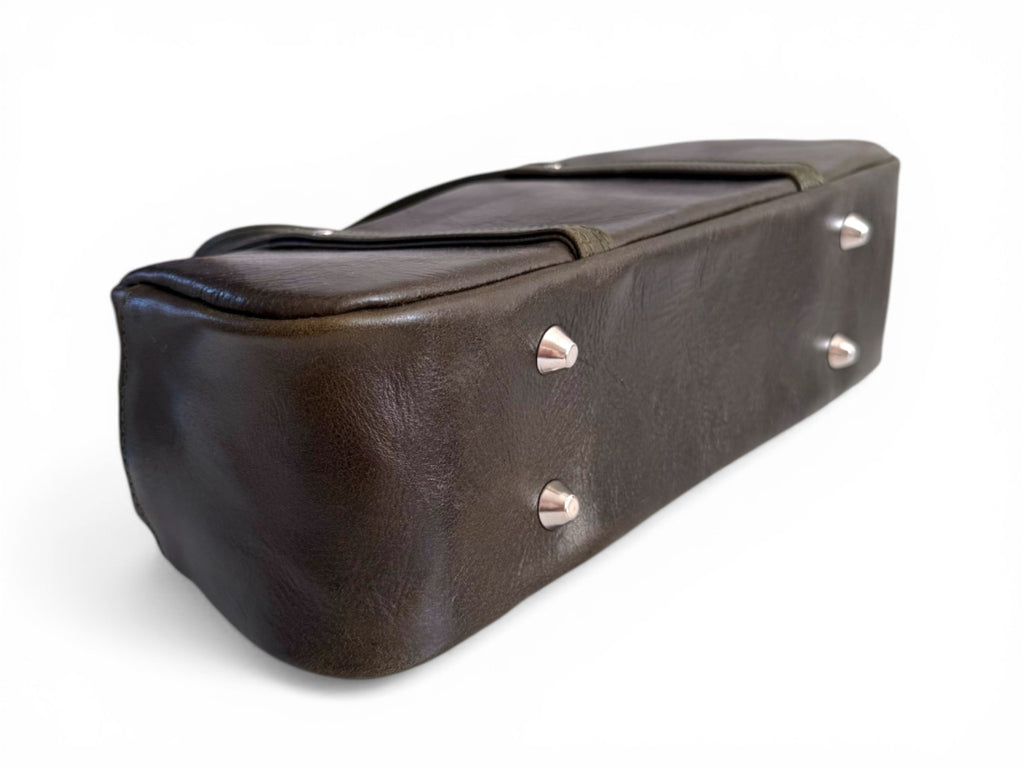 View of the bottom of a deep green handbag, showing the base of the bag with silver bag feet