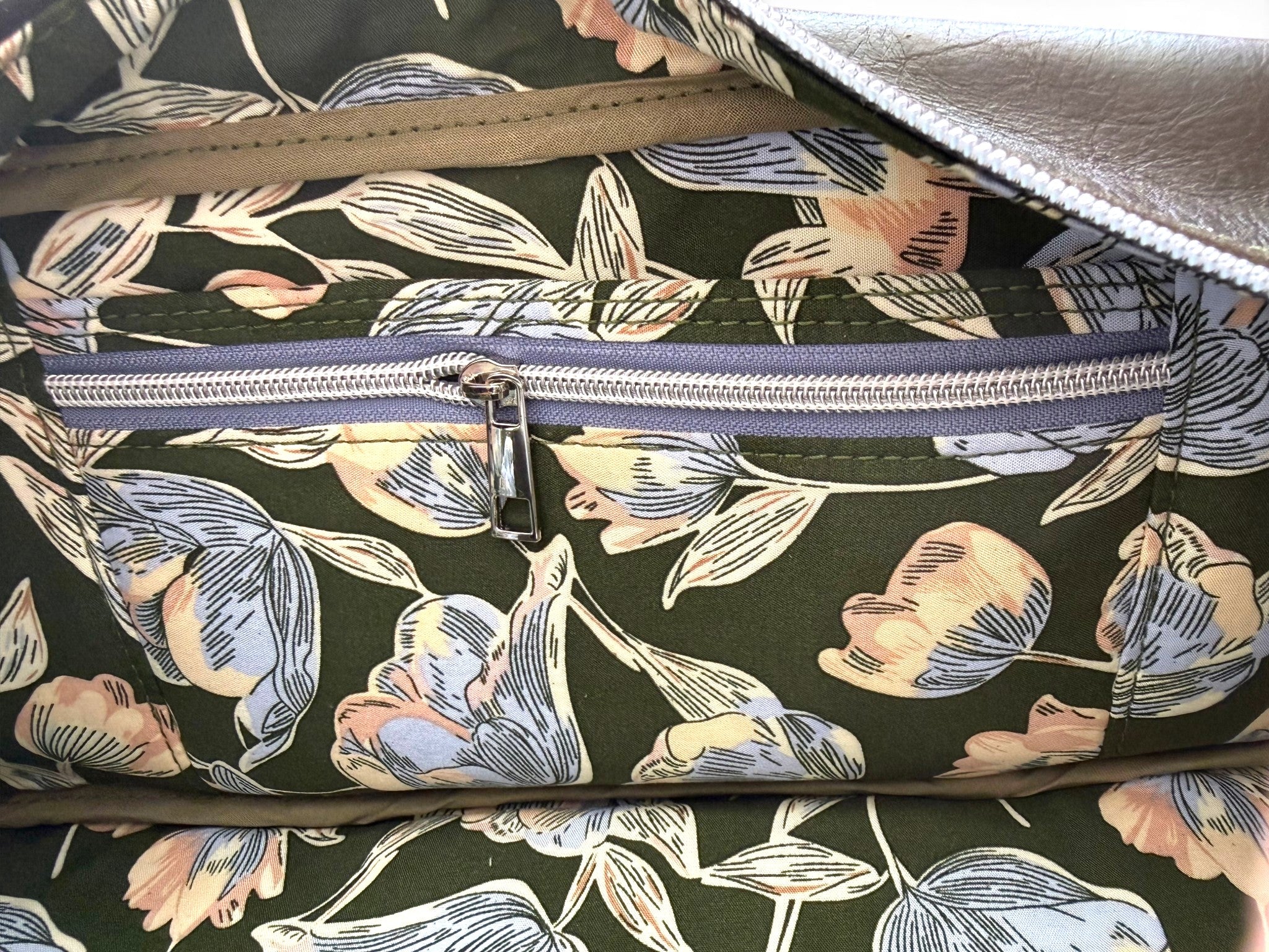 Closeup of the slip/zip pocket and green floral lining fabric inside the dark green leather handbag