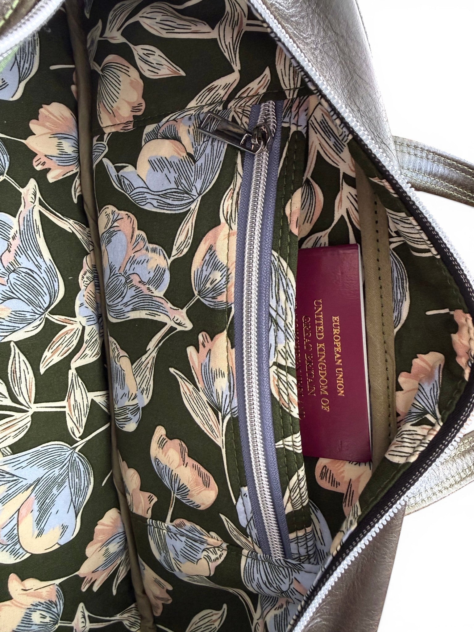 Floral-patterned bag lining with a visible slip/zip pocket, with a passport stored neatly in the slip pocket,  on a white background