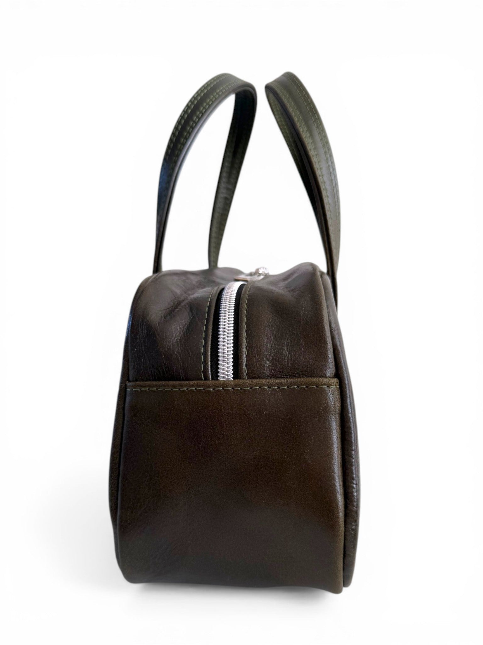 Side view of a dark green (almost black) leather handbag, showing the handles and silver zipper, against a white background