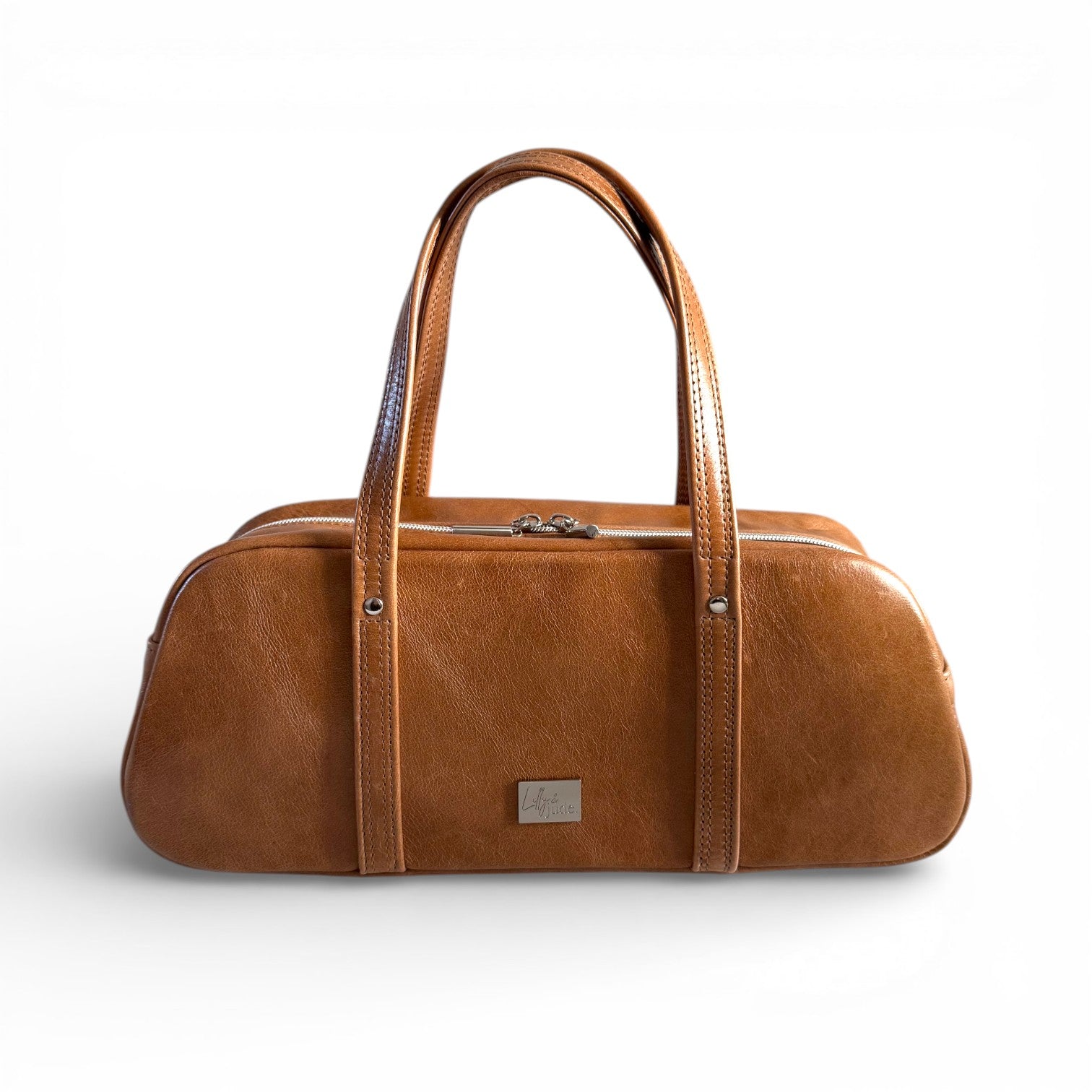 Tan brown leather, bowling style bag, against a white background. Handcarfted in the UK