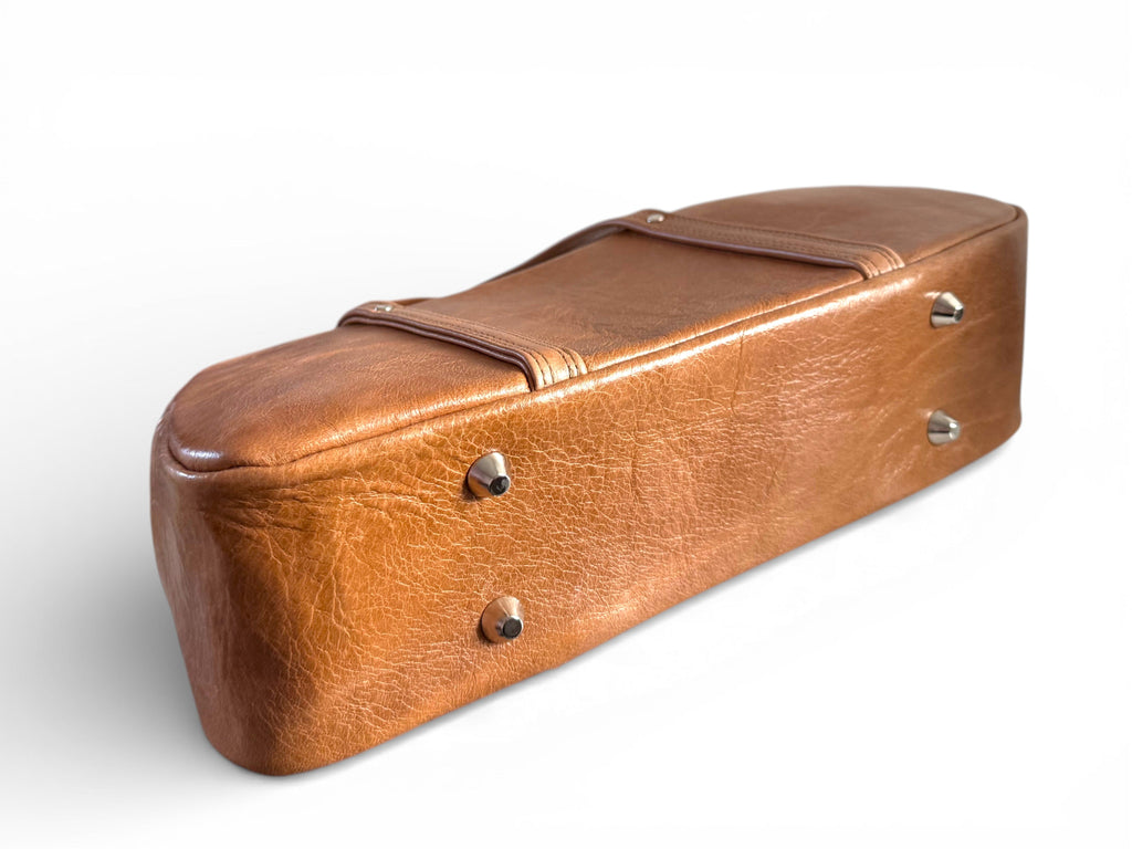 Bottom view of the base of a Tan brown coloured leather Cassie bowler bag, showing the silver bag feet at the base.